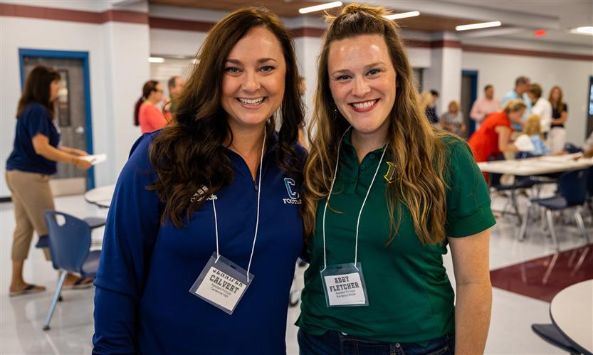 Two administrators stand together and smile